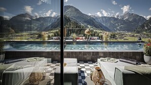 Zona de piscina con vista a montañas, suelo a cuadros y sillones de descanso.