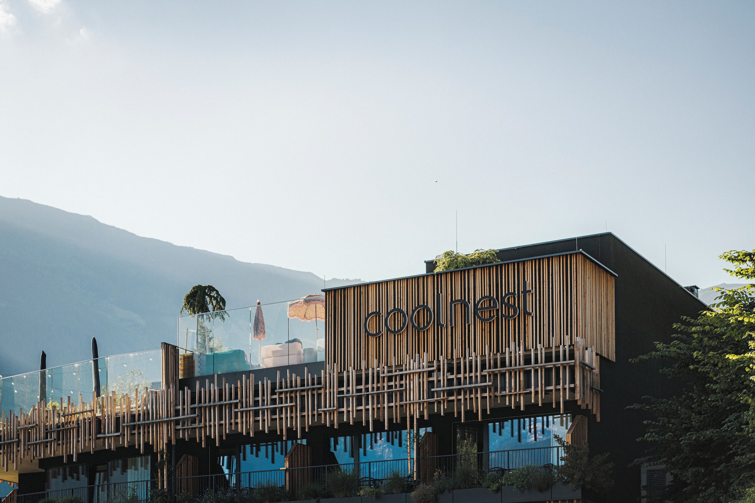 Un edificio moderno con fachada de madera y el nombre 'cool nest' a la vista.