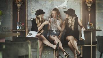Tres mujeres sentadas en una mesa de café, sosteniendo bebidas y mirando un menú.