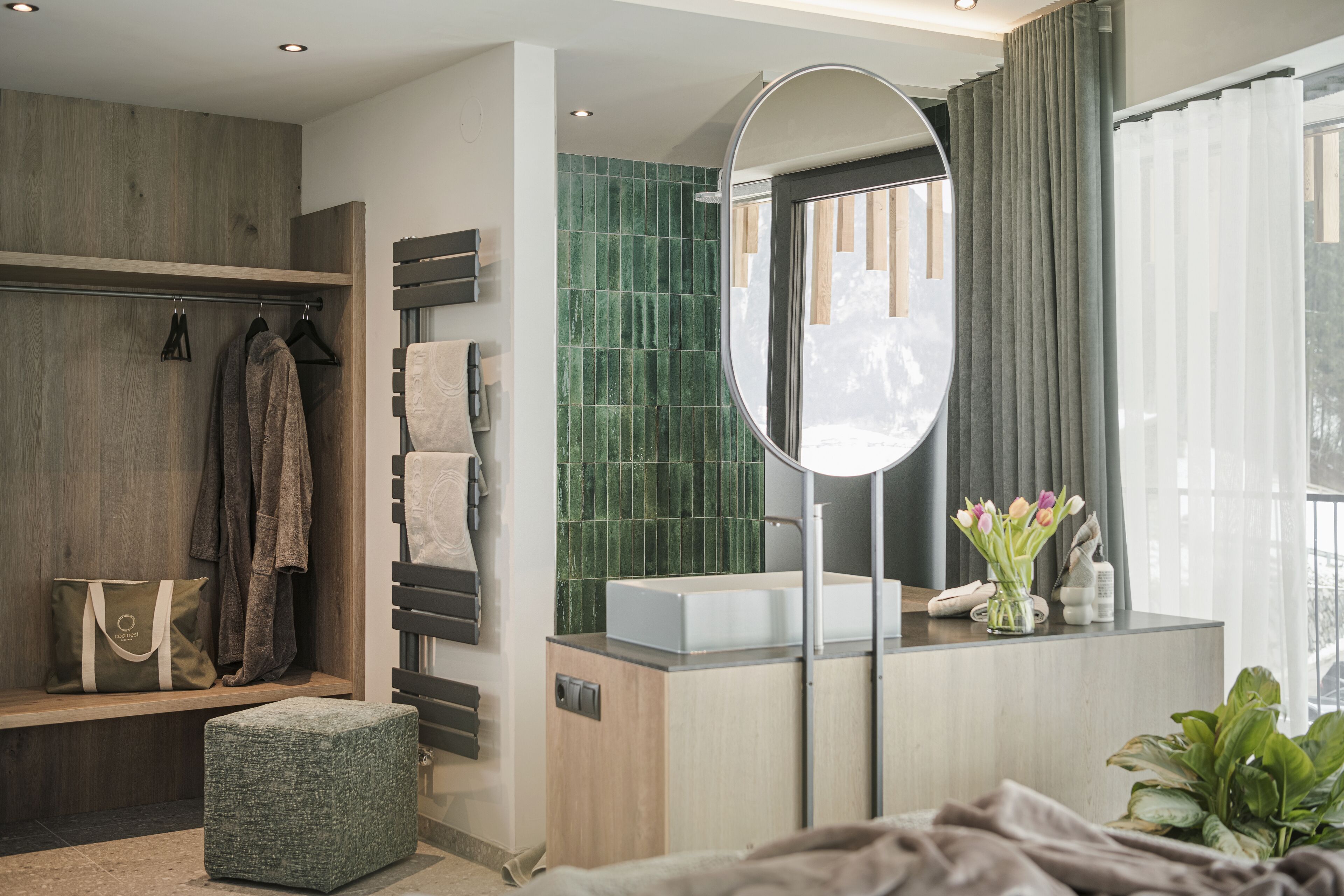 Une salle de bain moderne avec un meuble-lavabo en bois, un grand miroir et une zone de douche carrelée de carreaux verts.