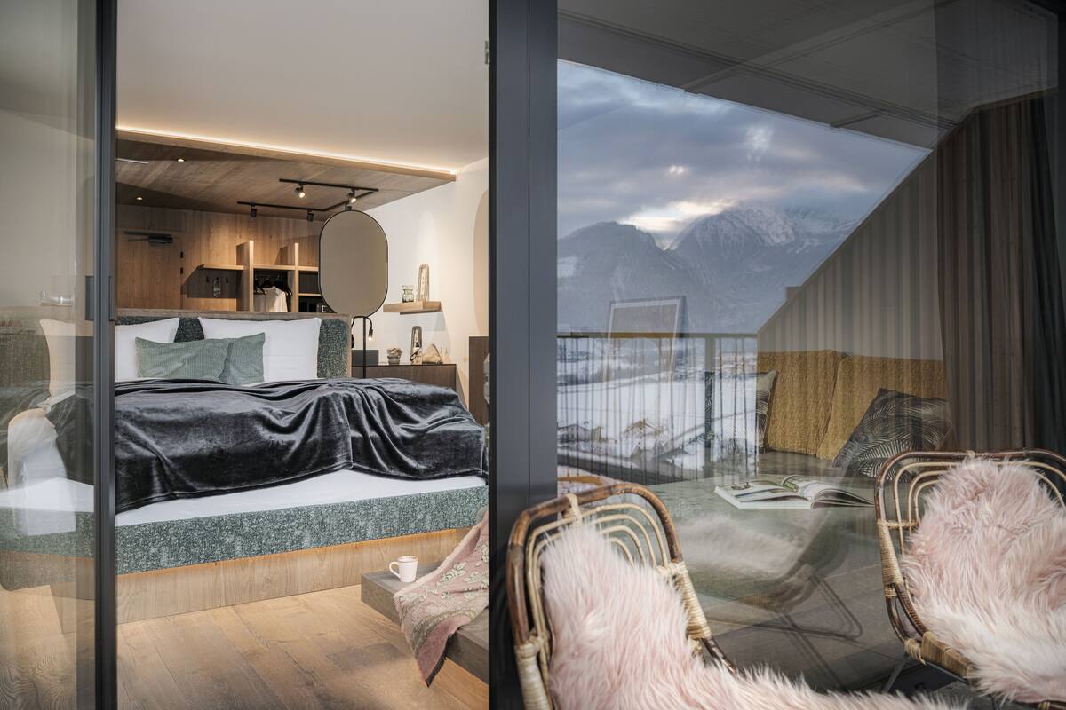Ein modernes Schlafzimmer mit einem großen Bett, einer Glaswand und Blick auf Berge.