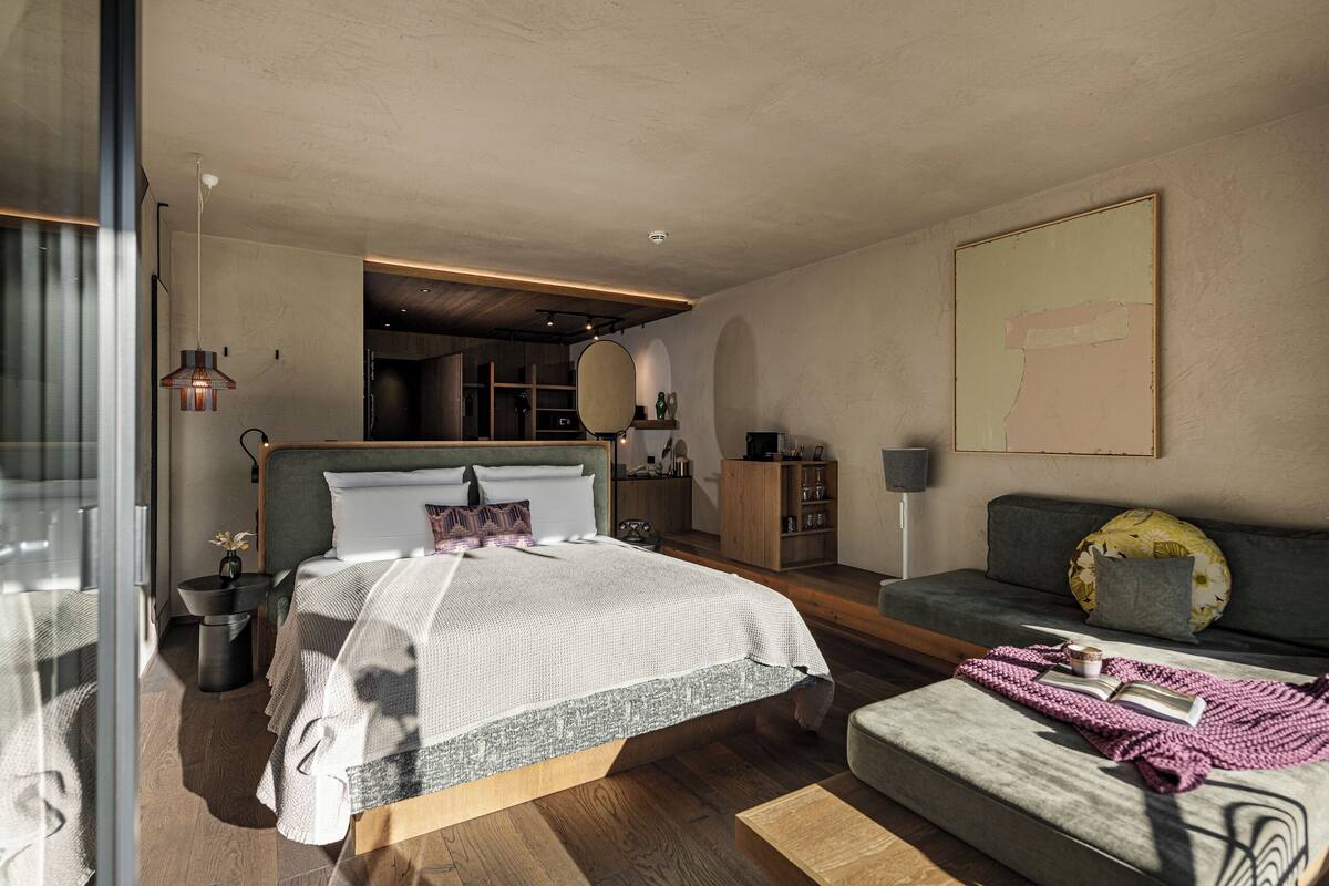 Ein modernes Schlafzimmer mit einem großen Bett, einer Couch und einem Esstisch.