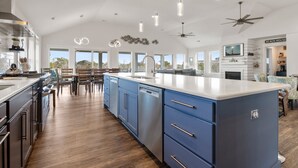 A spacious kitchen with a large island, modern appliances, and ample natural light from large windows. - All Inn and Then Some: Pool, Spa, Theater Room (Corolla)