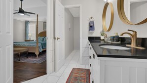 A modern bathroom with a black countertop, gold fixtures, and a large mirror. - The Sweet Home! Minutes from Mall of GA and Suwannee! (Sugar Hill)