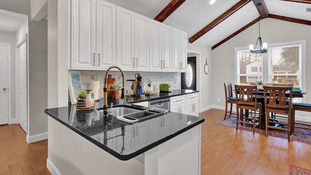 A kitchen with white cabinets, a black countertop, and wooden beams on the ceiling. - The Sweet Home! Minutes from Mall of GA and Suwannee! (Sugar Hill)