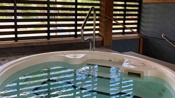 Un jacuzzi con una escalera metálica y una terraza de madera.