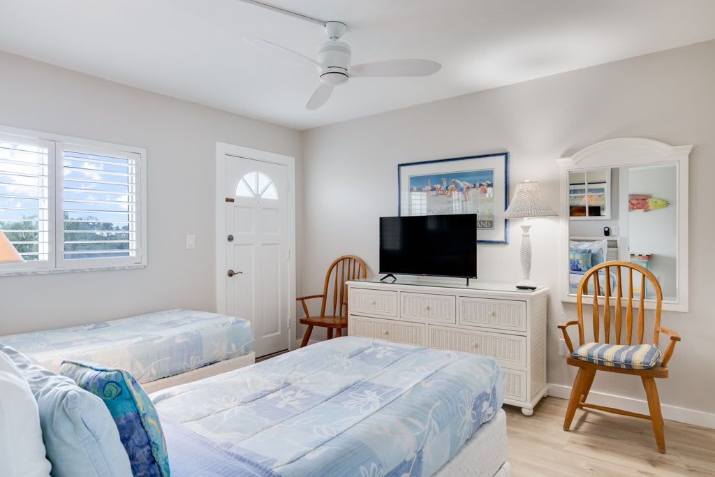 A bedroom with two beds, a television, a dresser, and a chair.
