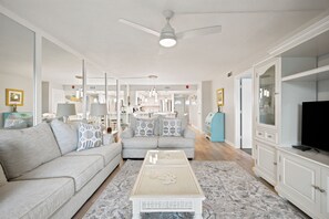 A modern living room with a grey sofa, a coffee table, and a television on a cabinet.