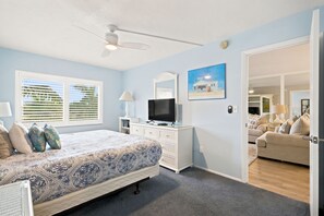 Ein Schlafzimmer mit einem Bett, einem Schminktisch, einem Fernseher und einem Bild an der Wand.