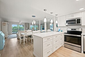 Una cocina moderna con armarios blancos, electrodomésticos de acero inoxidable e iluminación colgante.