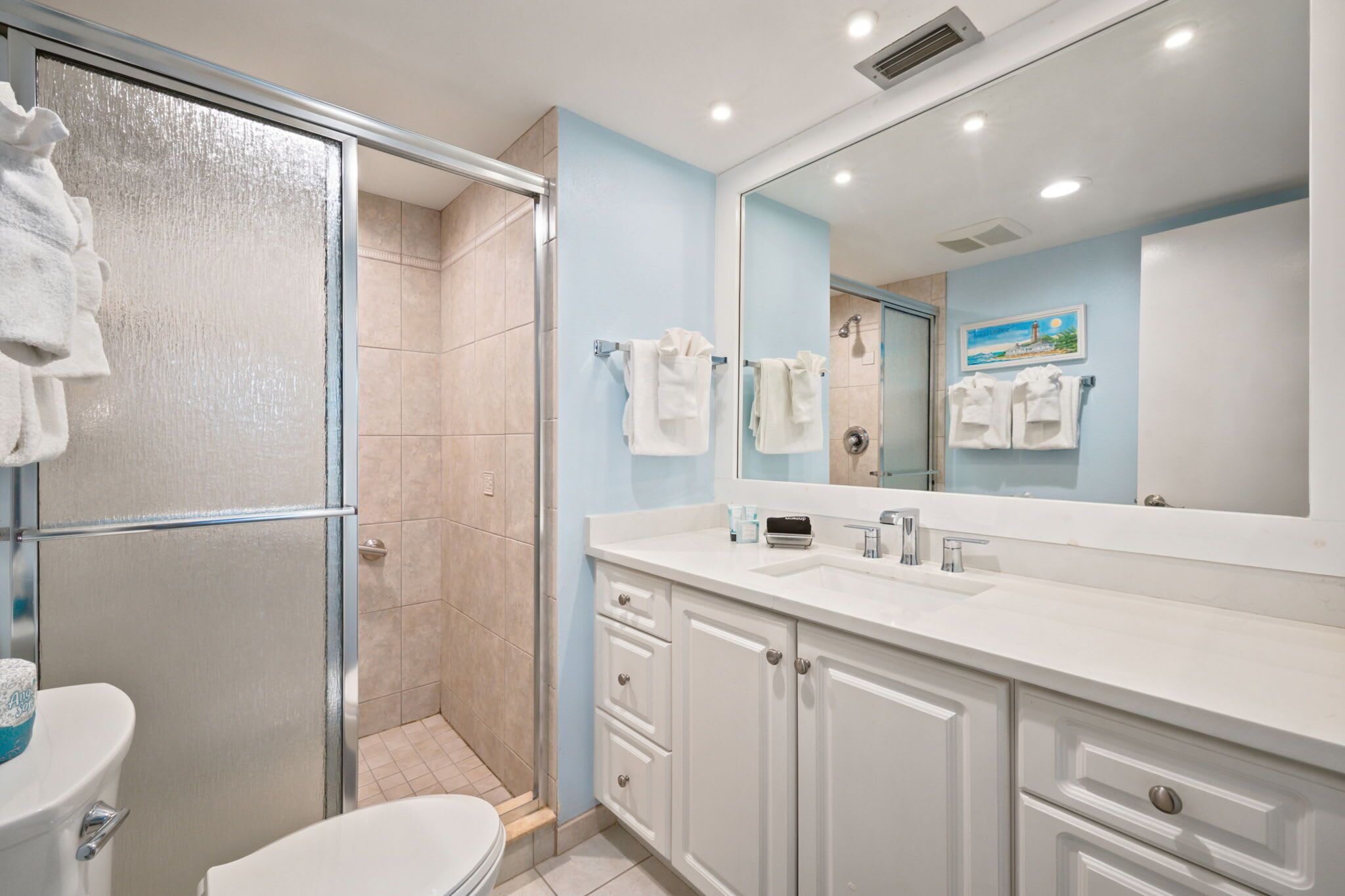 Une salle de bain équipée d’une douche, de toilettes, d’un lavabo et d’un grand miroir.