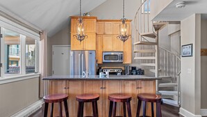 A kitchen with wooden cabinets, stainless steel appliances, and a central island with stools. - Blue Mesa Lodge 40B by AvantStay | Ski In/ Ski Out Unit w/ Balcony! (Telluride)
