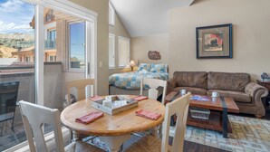 A cozy living room with a dining area, a sofa, and a painting on the wall.