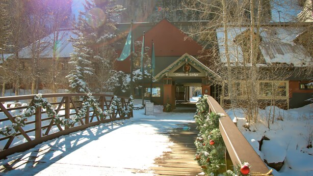 A wooden bridge leading to a lodge with a red roof and a sign that reads "Cimarron Lodge."