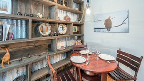 A rustic dining area with wooden shelves, a round wooden table, and chairs.