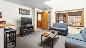 Una sala de estar con televisión, sofá y mesa de centro.