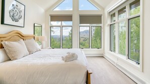 Ein Schlafzimmer mit einem großen Bett, mehreren Fenstern und Blick ins Freie.