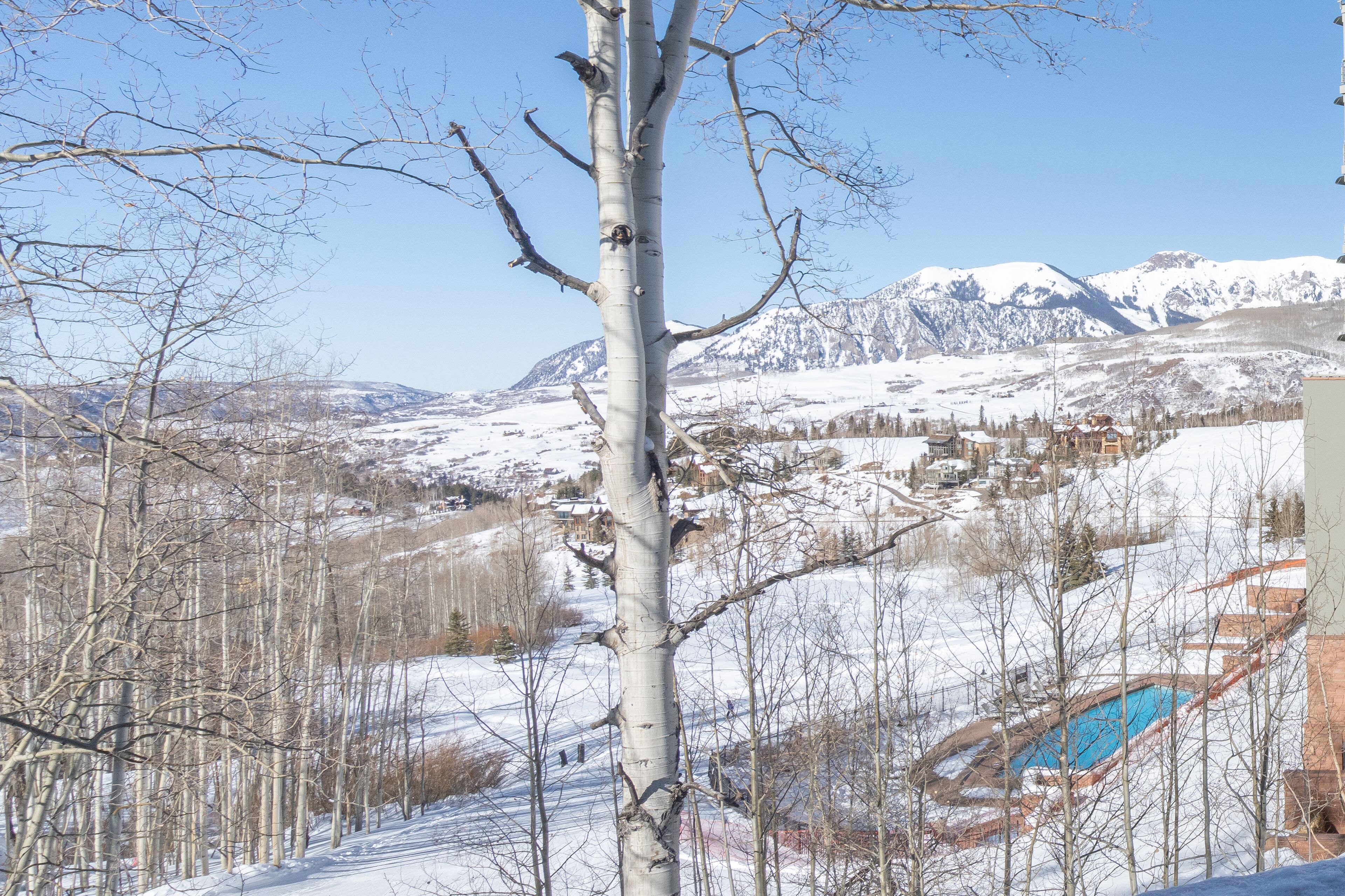 A snow-covered landscape with a clear view of a mountainous area and a small town in the background.