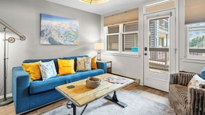 A living room with a blue sofa, a wooden coffee table, a lamp, and a painting on the wall. - Etta Place 6 by AvantStay | Ski In/ Ski Out Unit! (Telluride)