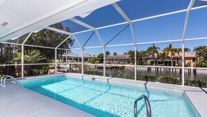 Ein Pool mit freiem Blick auf die Umgebung, einschließlich einer überdachten Terrasse und Blick auf ein Gewässer sowie Gebäude im Hintergrund.
