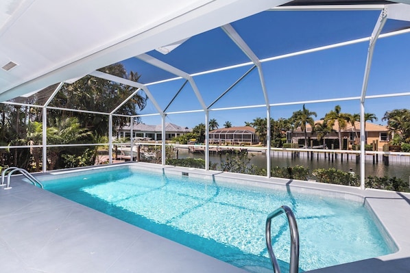 Una piscina con una vista despejada del entorno, que incluye un deck techado y una vista del cuerpo de agua y edificios al fondo.