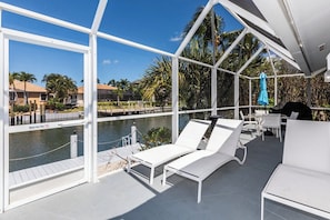 Un espacio al aire libre techado con sillones blancos y vista a la piscina.