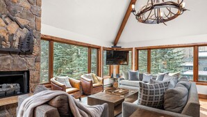 Una sala de estar acogedora con chimenea de piedra, ventanas amplias y una zona de estar confortable.