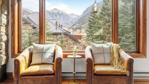 Una habitación con dos sillones de cuero orientados hacia una ventana grande que da a un paisaje montañoso.