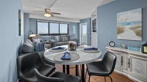 A dining area with a round table, black chairs, and a ceiling fan. - Direct Oceanfront Deluxe Suite Perfect View 3BR! (Myrtle Beach)