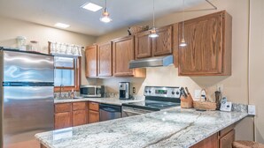 A modern kitchen with wooden cabinets, stainless steel appliances, and a marble countertop. - Ghostriders 5 by AvantStay | 2 Bedroom Condo Near Main Street, Hiking & Skiing | (Telluride)