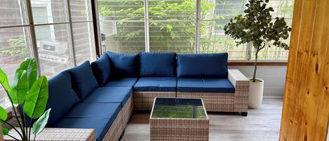 Une pièce chaleureuse avec un grand canapé d’angle, des meubles en osier et des plantes en pot.