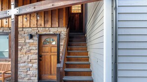 A wooden staircase leading to a stone and wood entrance, with a bench and a door with a window above it. - Hruza Hideout by AvantStay | Walkable Location + Free Ski Shuttle, Mountain View (Telluride)