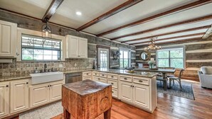 Una cocina amplia con armarios blancos, una isla de madera y un ventanal grande.