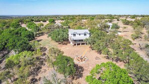 A two-story house surrounded by trees and a dry, open landscape. - Lux Ranch w/Hottub|AlamoSprings (Fredericksburg)