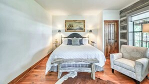 Un dormitorio con una cama grande, un banco de madera, una silla y un cuadro en la pared.