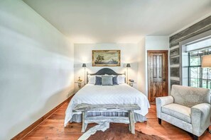 A bedroom with a large bed, a wooden bench, a chair, and a painting on the wall. - Lux Ranch w/Hottub|AlamoSprings (Fredericksburg)