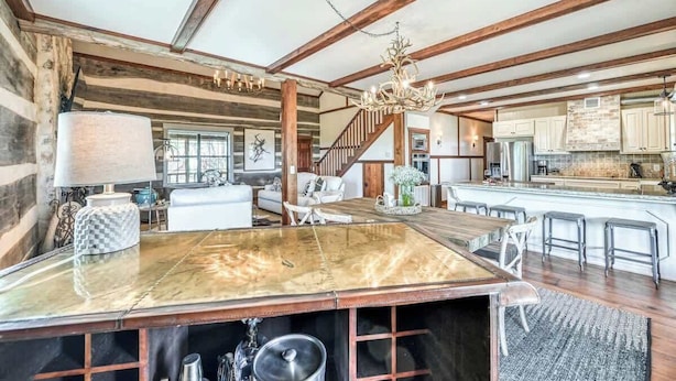 Una cocina amplia con una isla grande, vigas de madera y una araña.