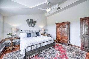 A bedroom with a bed, nightstands, a wooden wardrobe, a ceiling fan, and a patterned rug. - Lux Ranch w/Hottub|AlamoSprings (Fredericksburg)