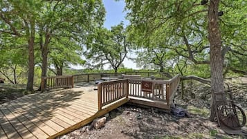 A wooden deck with a wooden fence, surrounded by trees.