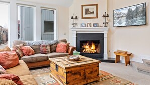 A cozy living room with a fireplace, a sofa, a coffee table, and a television. - Legacy House by AvantStay | Beautiful 4BDR Home in Great Location w/ Hot Tub (Telluride)