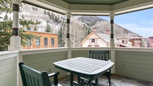 A covered patio with a table and chairs, a view of a mountain, and a building labeled "Telluride" in the background. - Legacy House by AvantStay | Beautiful 4BDR Home in Great Location w/ Hot Tub (Telluride)