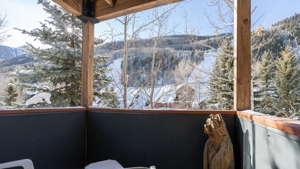 Ein Holzbalkon mit Blick auf eine verschneite Landschaft und Berge.