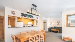 Ein geräumiger Wohnbereich mit einem Holzespeisetisch und Stühlen, einer Küche mit Holzschränken und einer gemütlichen Sitzecke mit Sofa und Couchtisch.