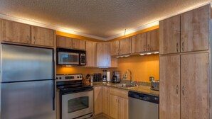 Una cocina moderna con gabinetes de madera, electrodomésticos de acero inoxidable y encimeras de granito.