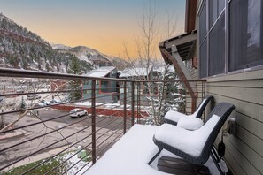 A balcony with snow-covered chairs, a view of a snowy mountain, and a parking area with cars. - Owl Meadows 24 by AvantStay | Walking Distance to Town & Slopes! (Telluride)