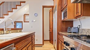 Une cuisine avec des meubles en bois, une cuisinière en acier inoxydable et un plan de travail en granit.