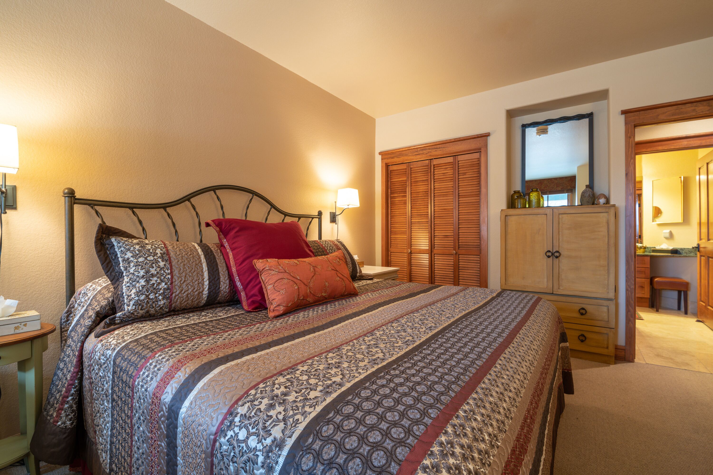 Een slaapkamer met een bed, nachtkastjes, een kledingkast en een spiegel.