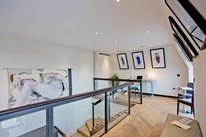 A modern interior with a staircase, glass railing, and artwork on the walls. - 3-bed Penthouse (London)