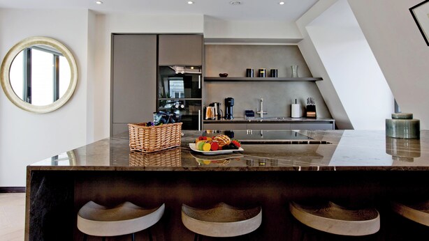 A modern kitchen with a marble countertop, a round mirror, and a built-in oven. - 2-bed Deluxe 621 (London)