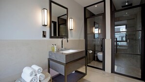 A modern bathroom with a marble sink, a large mirror, and a glass-enclosed shower. - 2-bed Deluxe 621 (London)